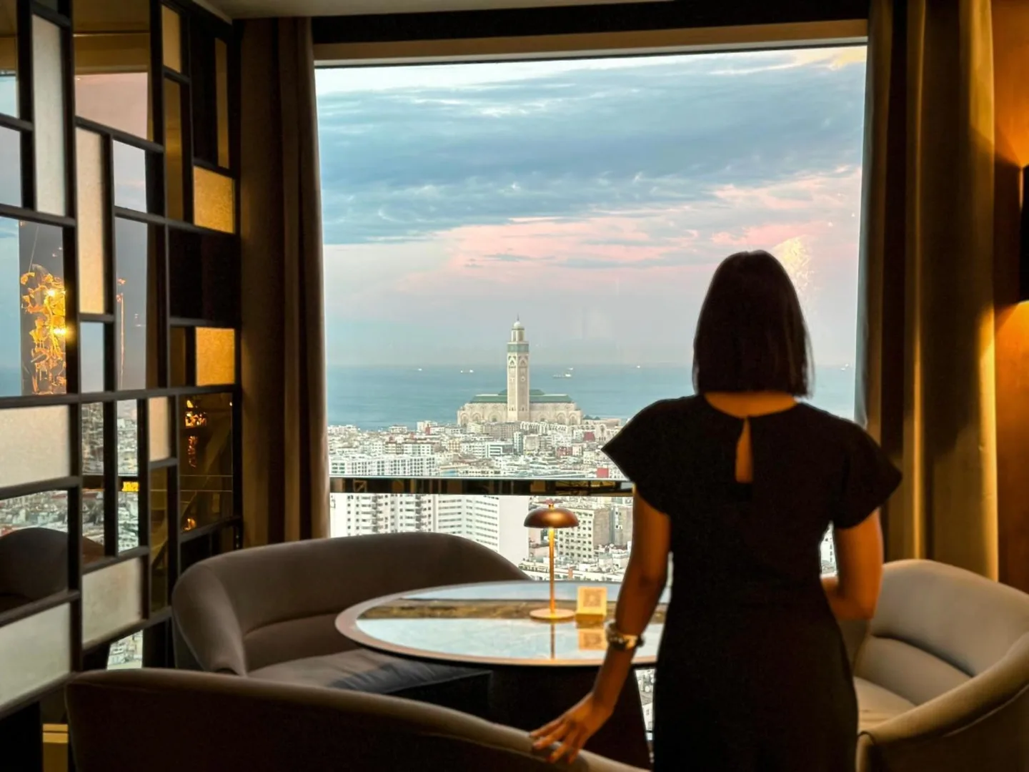 A contributor at a Casablanca window looking towards Hassan II Mosque at dusk